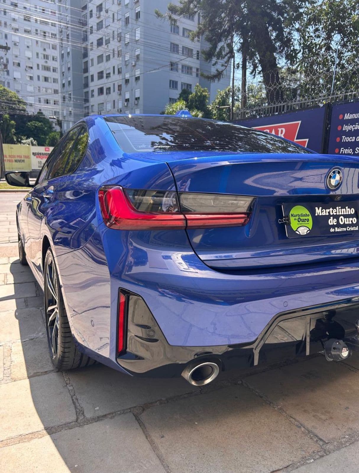 BMW azul com pintura espelhada vista traseira em ambiente urbano