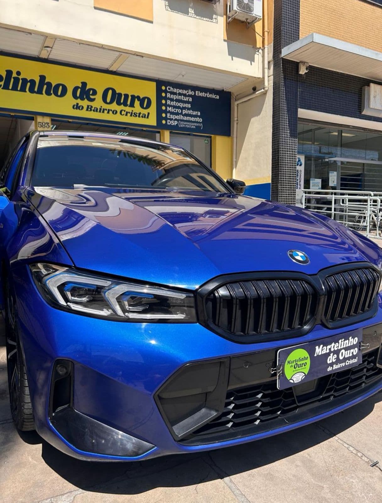 BMW azul com acabamento espelhado em frente ao Martelinho de Ouro do Bairro Cristal, Porto Alegre