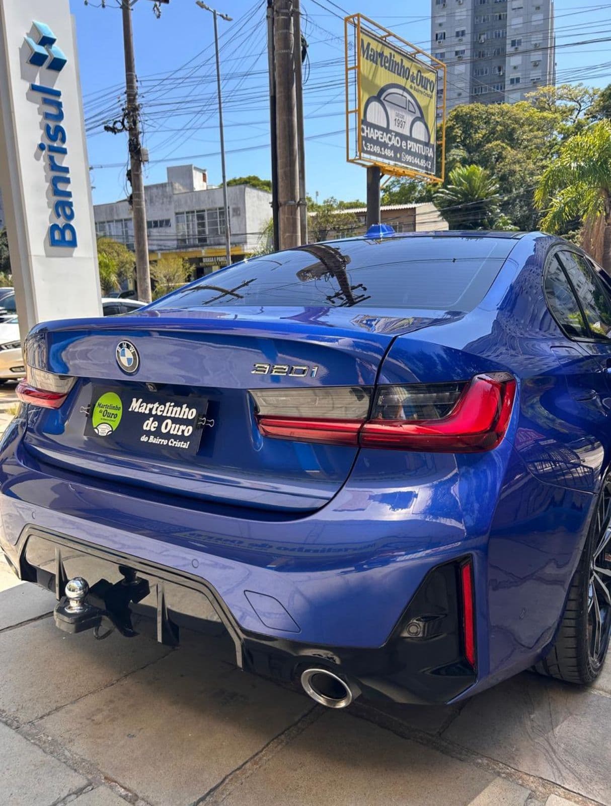 BMW 320i azul traseira com placa promocional Martelinho de Ouro